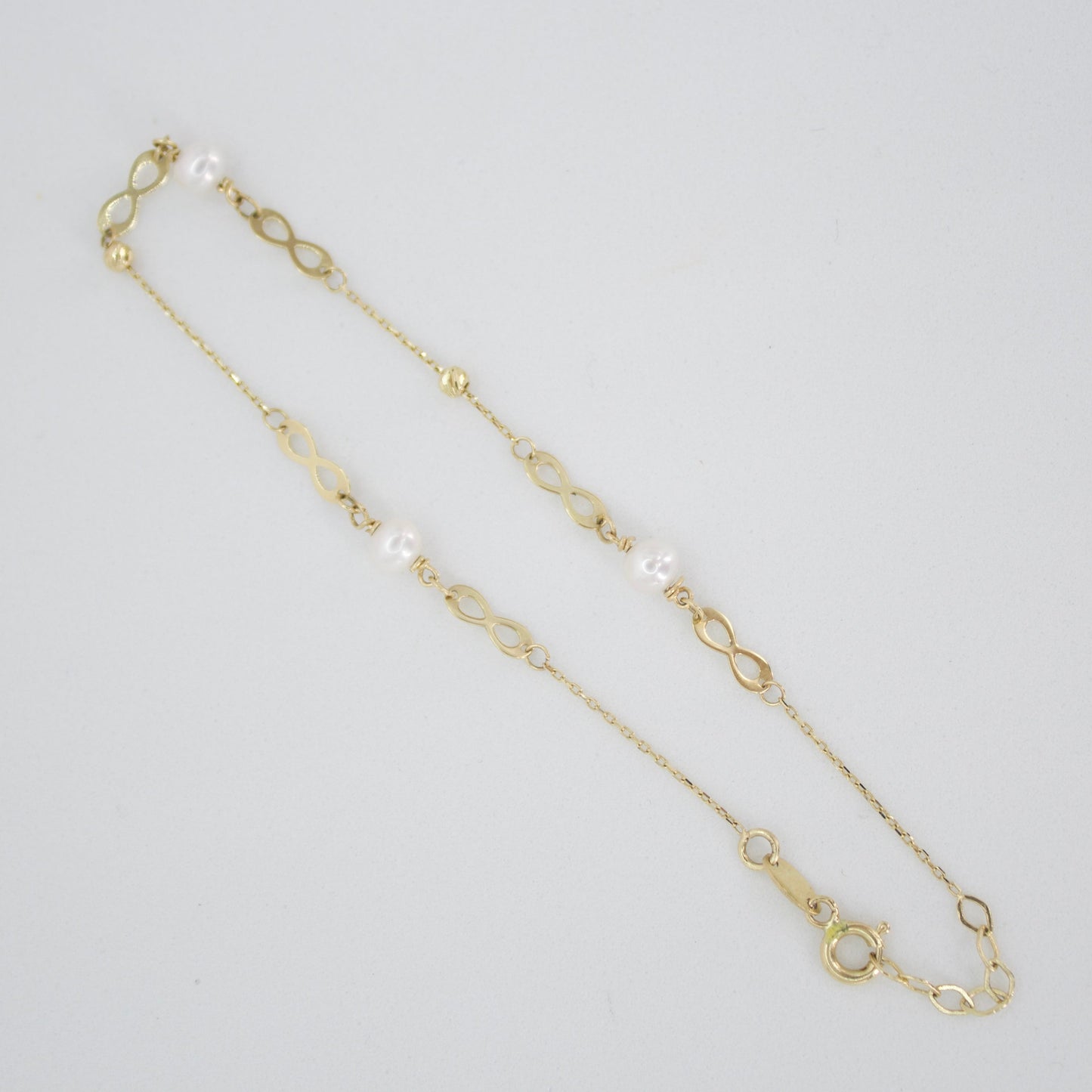 Pulsera infinitos con perla en oro amarillo 14k.