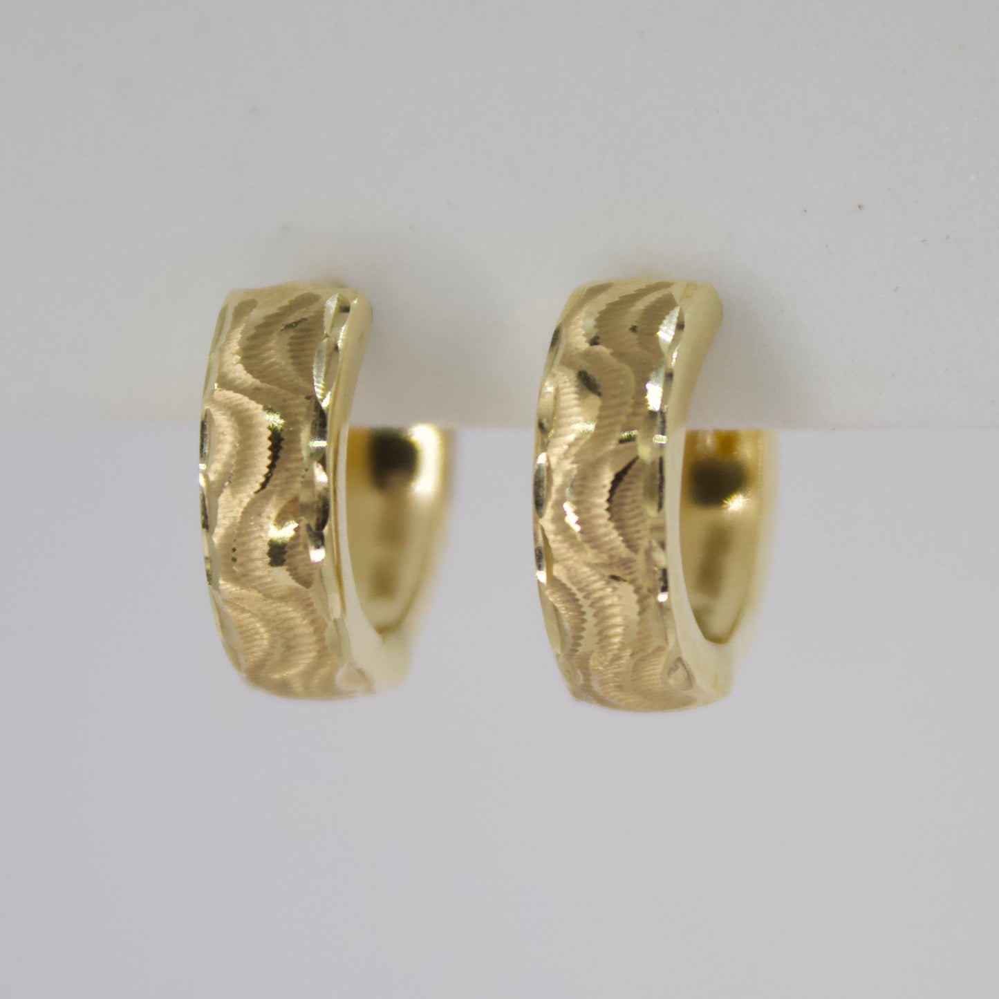 Aretes Huggies en oro facetado 14k.